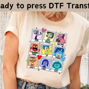 以下が含まれることがあります： クリーム色のTシャツに、映画「インサイド・ヘッド」のキャラクターのグラフィックがプリントされています。各キャラクターは、名前が書かれた額縁の中に描かれています。キャラクターは、恐怖、嫌悪、ビング・ボン、怒り、喜び、悲しみ、不安、退屈、そして羨望です。