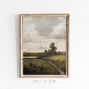May include: A framed painting of a landscape with a field, trees, and a cloudy sky. The painting is in a light wood frame.