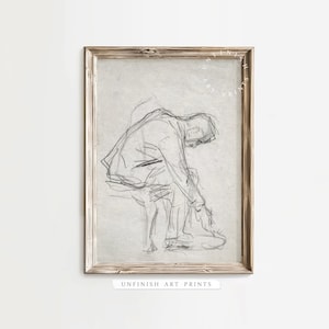 May include: A black and white line drawing of a person sitting down and tying their shoes. The drawing is framed in a light wood frame. The text "UNFINISH ART PRINTS" is printed below the frame.