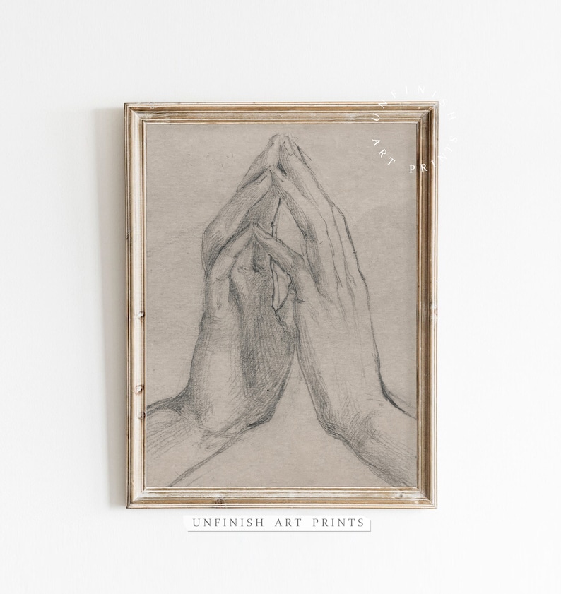 Pode incluir: Um desenho a l&aacute;pis preto e branco de duas m&atilde;os juntas em ora&ccedil;&atilde;o. O desenho est&aacute; emoldurado em uma moldura de madeira clara.