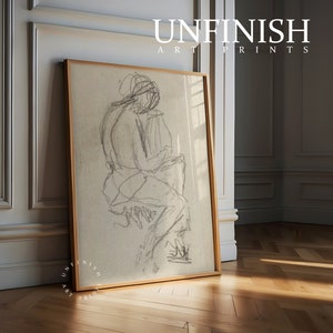 May include: A framed black and white pencil sketch of a person sitting down. The sketch is on a beige background and the frame is a light wood color.