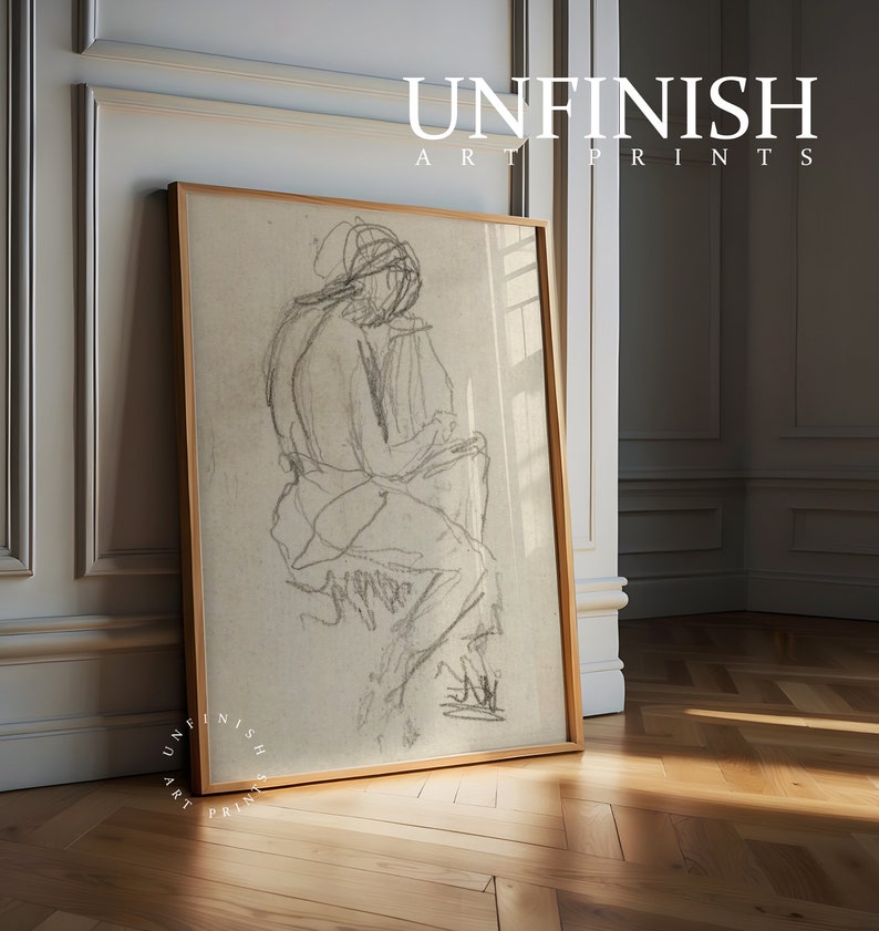 May include: A framed black and white pencil sketch of a person sitting down. The sketch is on a beige background and the frame is a light wood color.