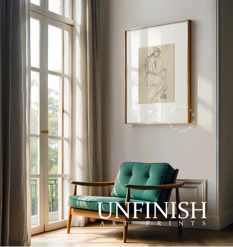 May include: A green armchair with wooden arms and legs sits in a room with a large window and a framed black and white drawing of a person on the wall. The text "UNFINISH ART PRINTS" is on the floor in front of the chair.