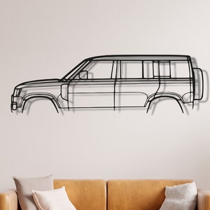 May include: A black metal outline of a car, mounted on a white wall above a brown leather sofa. The sofa has two cushions on it.