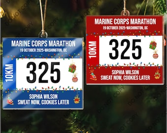 May include: Two rectangular Christmas ornaments featuring a Marine Corps Marathon design. One is blue, the other red, both with the text "Marine Corps Marathon" and "19 October 2025-Washington, DC". Each has the number "325" and the text "Sweat Now, Cookies Later".