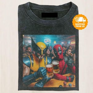 May include: Dark grey t-shirt with a graphic of Wolverine and Deadpool in a bar, toasting with beers. Wolverine is smoking. The image has a vintage, distressed appearance, with a crowd in the background.