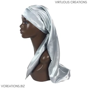 May include: A silver satin hair scarf with a long tail. The scarf is tied around a mannequin's head.