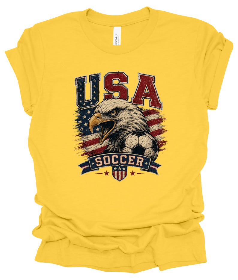 Peut inclure: Un t-shirt jaune vif &agrave; manches courtes avec une impression graphique repr&eacute;sentant un pygargue &agrave; t&ecirc;te blanche, un ballon de football et le drapeau am&eacute;ricain. Le texte "USA" est &eacute;crit en grandes lettres rouges et bleues au-dessus de l'aigle.