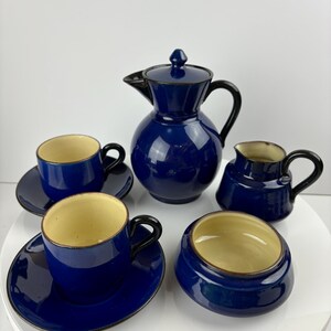 May include: A blue and cream ceramic tea set with a teapot, creamer, sugar bowl, and two cups and saucers.