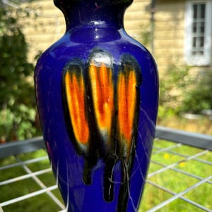 May include: A cobalt blue ceramic vase with a drip glaze design in shades of orange and black.