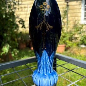 May include: A blue and gold ceramic vase with a floral design. The vase has a bulbous base and a narrow neck.