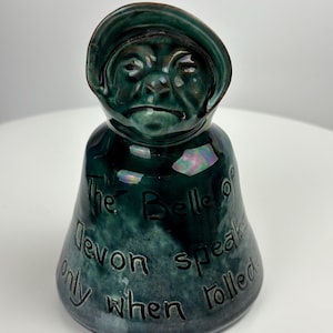 May include: A green ceramic bell with a hooded figure face and the text "The Belle of Devon speaks only when tolled".