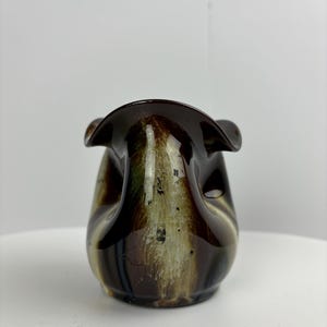 Può includere: Un vaso in ceramica marrone e bianco con un design ondulato unico. Il vaso ha una finitura lucida e un'ampia apertura.