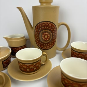 May include: A vintage brown and orange ceramic tea set with a geometric pattern. The set includes a teapot, creamer, sugar bowl, and four cups and saucers.