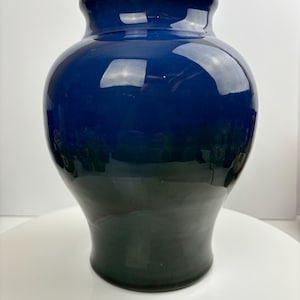 May include: A dark blue ceramic vase with a gradient effect, transitioning from a deep blue to a darker shade of blue at the bottom.