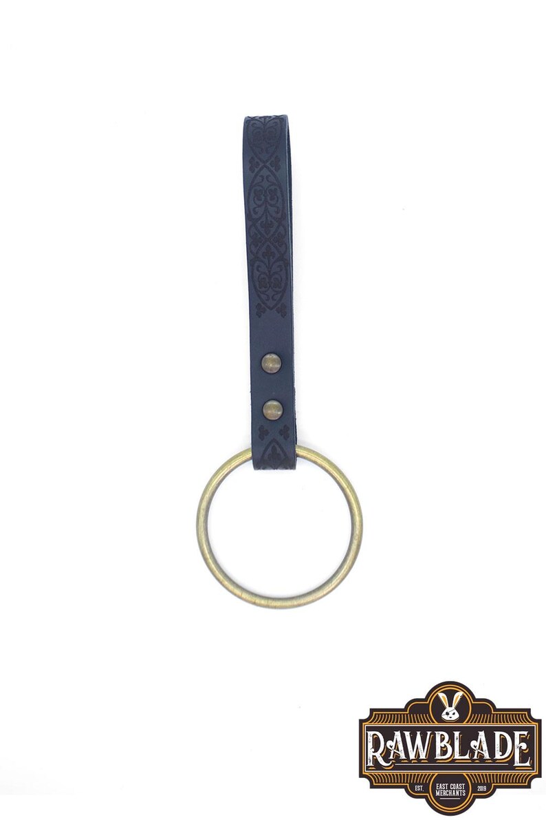 May include: A black leather sword hanger with an ornate design and a brass ring.