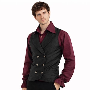 May include: A black double-breasted vest with gold buttons. The vest is worn over a burgundy long-sleeved shirt with a collared neckline and ruffled cuffs. The vest has a textured appearance. The outfit is formal.