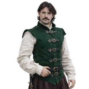May include: A dark green suede vest with black leather straps and brass buckles. The vest has a high collar and shoulder accents. The garment is part of a historical or fantasy costume.
