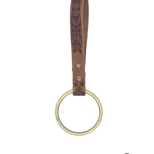 May include: A brown leather key chain with a brass ring and a decorative pattern. The key chain is made by Rawblade East Coast Merchants.
