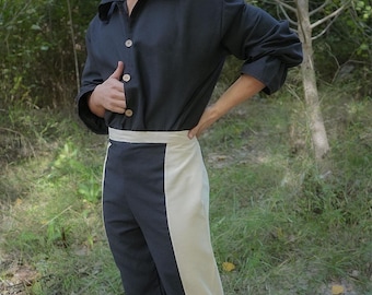 May include: A person wearing a black button-down shirt and two-tone pants with a cream-colored stripe. The person is also wearing brown boots. The Rawblade logo is visible in the bottom right corner.