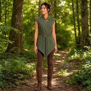 May include: An olive green sleeveless tunic featuring a mandarin collar with a toggle closure, a braided waist belt with a circular buckle, and a pointed hemline, paired with brown fitted trousers and matching brown knee-high boots.