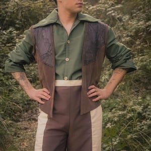 May include: A person wearing a green shirt, brown waistcoat with dark patches, and brown and cream trousers. The Rawblade logo is in the bottom right corner. The outfit has a vintage, outdoorsy aesthetic.