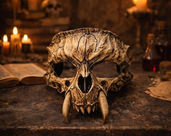 May include: A detailed, weathered skull mask with large fangs, set on a stone surface. The mask is a beige color with dark cracks, and is surrounded by lit candles and an open book, creating a gothic or fantasy theme.