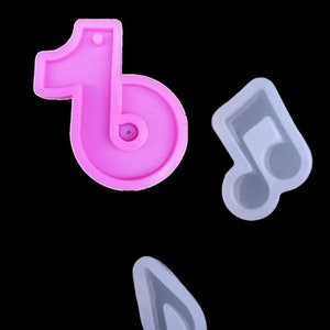 May include: Two silicone molds for making resin crafts. One mold is pink and shaped like the TikTok logo. The other mold is gray and shaped like a musical note.
