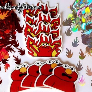 May include: Four red Elmo-like characters with wide eyes and open mouths are surrounded by red and iridescent flame-shaped glitter. The characters are on a white background. The text "Resinmoldsandglitter.com" is in the top left corner of the image.