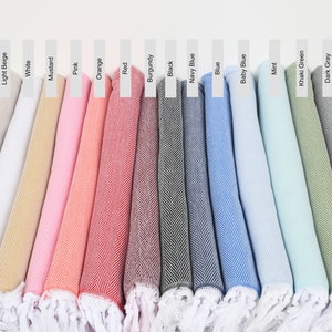 Könnte beinhalten: Eine Sammlung von 16 türkischen Handtüchern in verschiedenen Farben, darunter Braun, Hellbeige, Weiß, Senf, Rosa, Orange, Rot, Burgunder, Schwarz, Marineblau, Blau, Babyblau, Minze, Khaki, Dunkelgrau und Hellgrau. Die Handtücher sind gefaltet und in einer Reihe angeordnet, wobei die Farben von dunkel nach hell übergehen.