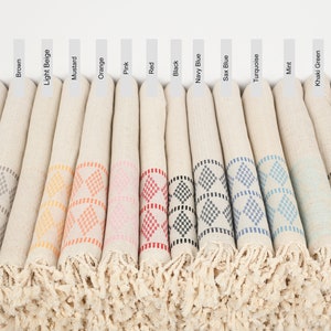 May include: A set of 14 rolled up towels with fringe edges. Each towel has a different colored diamond pattern in the center. The colors are gray, brown, light beige, mustard, orange, pink, red, black, navy blue, sax blue, turquoise, mint, khaki green, and light gray.