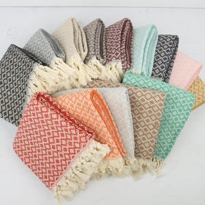May include: A selection of folded cotton towels with diamond patterns and fringed edges. The towels are in a range of colours, such as red, orange, and green. They are arranged in a fan shape, showcasing the variety.