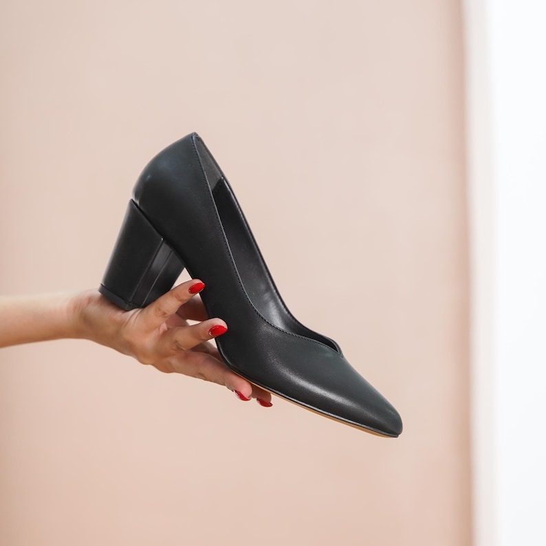 Hand holding a black vegan leather bridal block heel, showcasing the sleek upper, medium high block heel, and luxurious finish by Hyl Wedding Shoes.