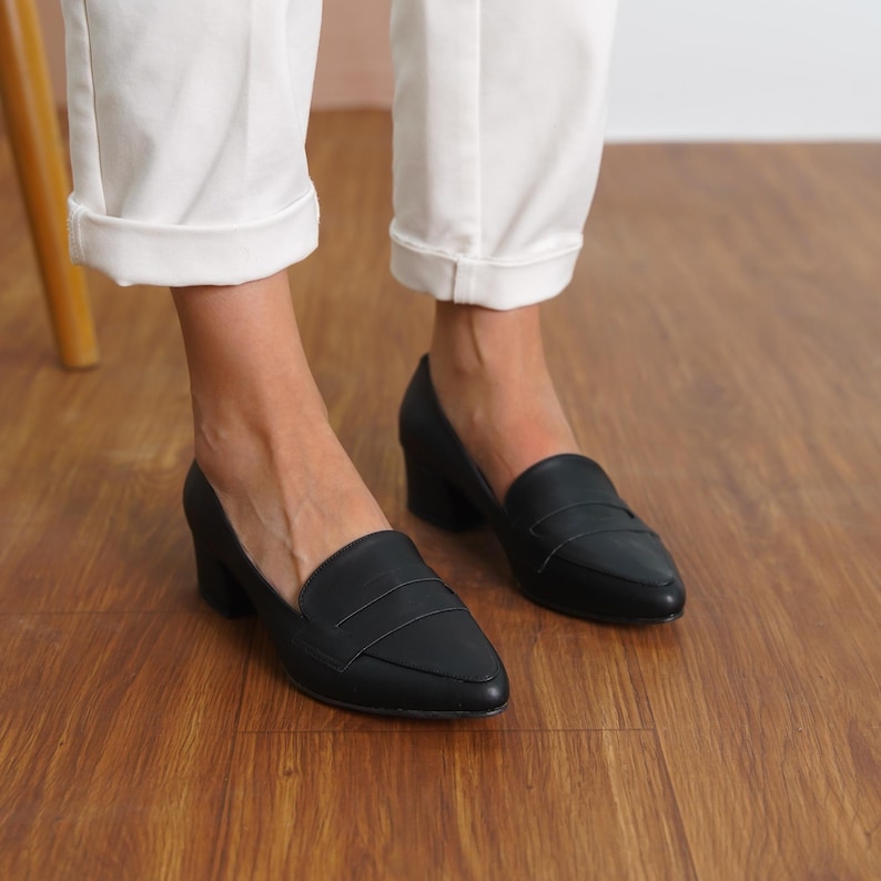 Front view of a woman standing in black vegan leather low block heel loafers, capturing the sophisticated look and sleek design hyl wedding short heels.