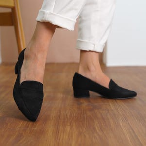 Side view of a woman walking in black vegan suede bridal block low heel loafers, showcasing the sleek and stylish design hyl wedding short heels.