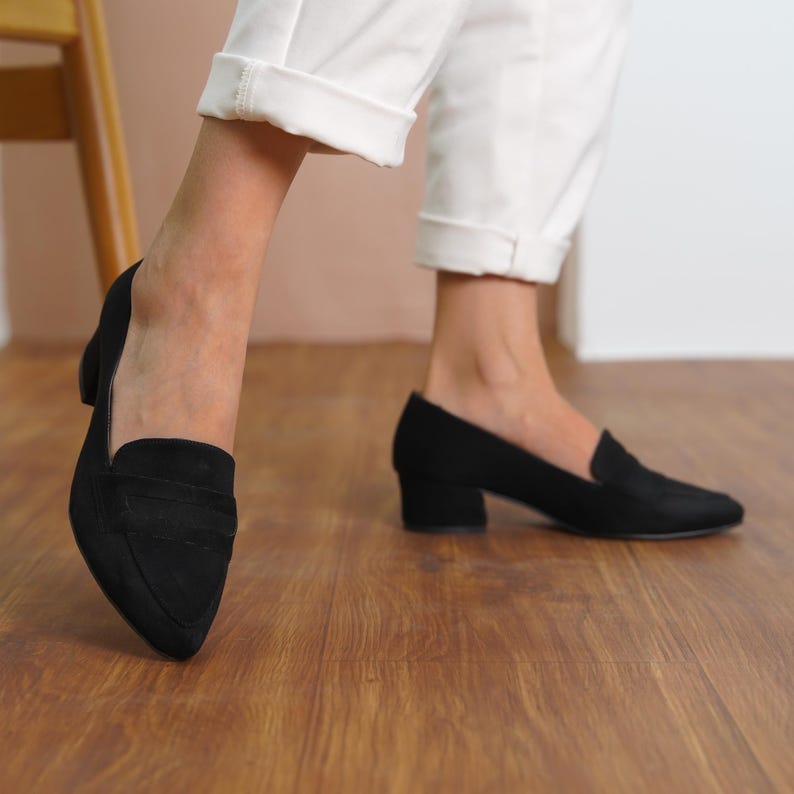 Side view of a woman walking in black vegan suede bridal block low heel loafers, showcasing the sleek and stylish design hyl wedding short heels.
