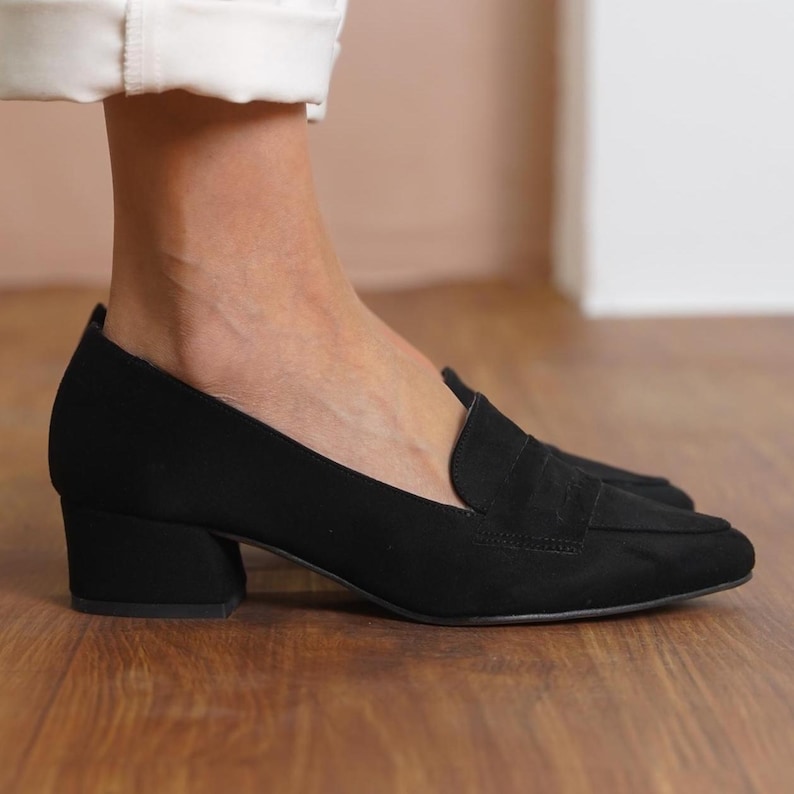 Detailed shot of handmade black loafers, highlighting the sleek pointed toe and sturdy low block heel suitable for office and special events.