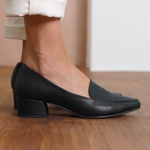 Detailed shot of handmade black loafers, highlighting the sleek pointed toe and sturdy low block heel suitable for office and special events.
