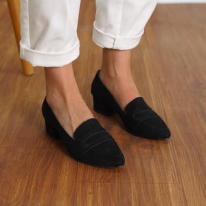 Front view of a woman standing in black vegan suede low block heel loafers, capturing the sophisticated look and sleek design hyl wedding short heels.