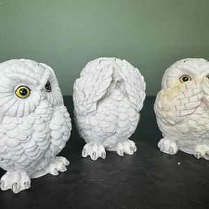 May include: Three white owl figurines, each with a different hand gesture representing "see no evil", "hear no evil", and "speak no evil".