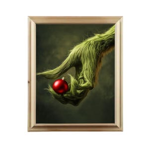 May include: A green, furry hand holding a red Christmas ornament. The hand is against a dark green background.