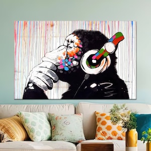 May include: A colorful abstract painting of a monkey wearing headphones. The monkey is sitting with its chin on its hand and looking to the side. The background is a white canvas with colorful paint splatters.