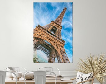 May include: A low angle view of the Eiffel Tower in Paris, France. The tower is made of metal and is a popular tourist destination. The sky is blue with white clouds.