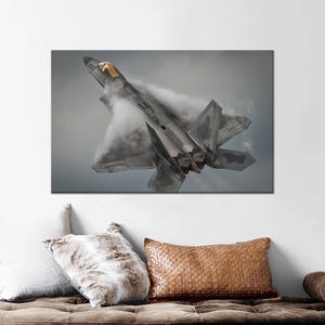 Peut inclure: Un avion de chasse gris volant dans les airs, laissant une traînée de fumée blanche derrière lui.