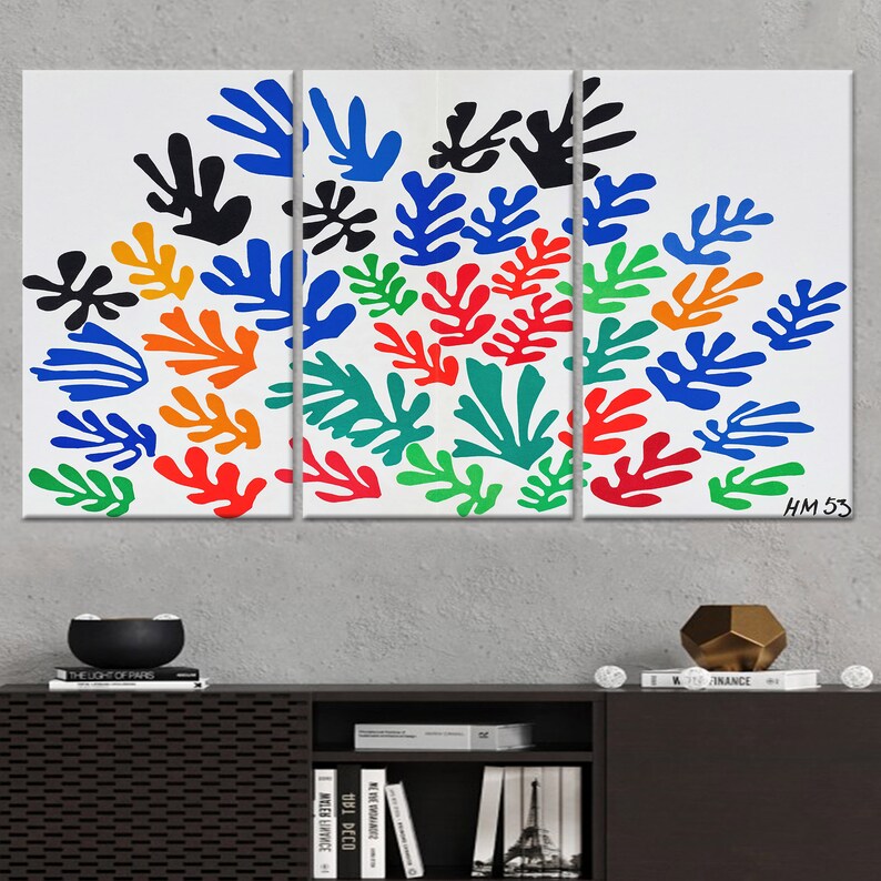 May include: A three-panel canvas print featuring a colorful abstract design of stylized leaves in shades of blue, green, orange, red, and black. The print is signed "HM 53" in the bottom right corner.