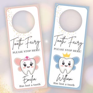 Op de afbeelding: Twee rechthoekige deurhangers met ronde uitsparingen aan de bovenkant. De een heeft een roze rand, de ander een blauwe rand. Beide bevatten de tekst Tooth Fairy PLEASE STOP HERE!, een cartoon-tand met vleugels en de namen Emilia of William.