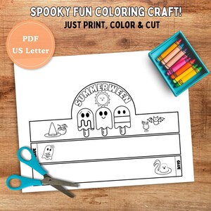 May include: A white paper craft with the text "SUMMERWEEN" and illustrations of ghosts and ice pops. The craft includes the text "JUST PRINT, COLOR & CUT" and "PDF US Letter". A pair of blue scissors and a box of crayons are also visible.