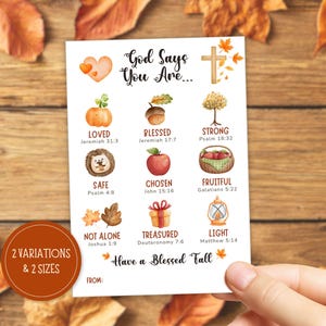 May include: A white card featuring the text God Says You Are and Have a Blessed Fall, decorated with autumn-themed illustrations including a pumpkin, acorn, tree, hedgehog, apple, basket, leaves, gift, and lantern, each paired with a Bible verse.