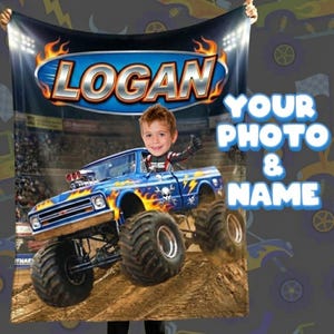 May include: A personalized blanket featuring a blue monster truck design with flames and skull graphics. The name "LOGAN" is displayed above the truck, with the text "YOUR PHOTO & NAME" on the right. The blanket is held up by a person.