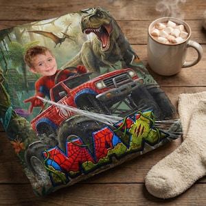 May include: A personalized blanket featuring a child's face superimposed on a Spider-Man-themed monster truck design, with a Tyrannosaurus Rex and jungle background. The blanket has the name "MAX" in a graffiti style. A mug of hot chocolate and a pair of socks are also visible.